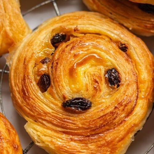 Närbild av gyllene, frasigt wienerbröd med russin