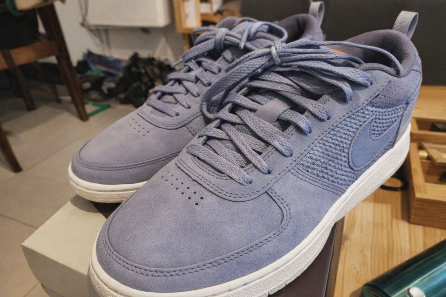 Ett par blå sneakers står på en skokartong i ett hem.